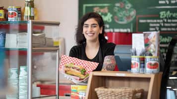 Una persona sosteniendo un sándwich envuelto en papel de cuadros.
