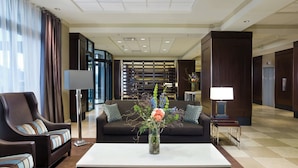 A modern hotel lobby with a sofa, armchairs, a coffee table, and a decorative vase with flowers. - Sheraton Niagara Falls (Niagara Falls)