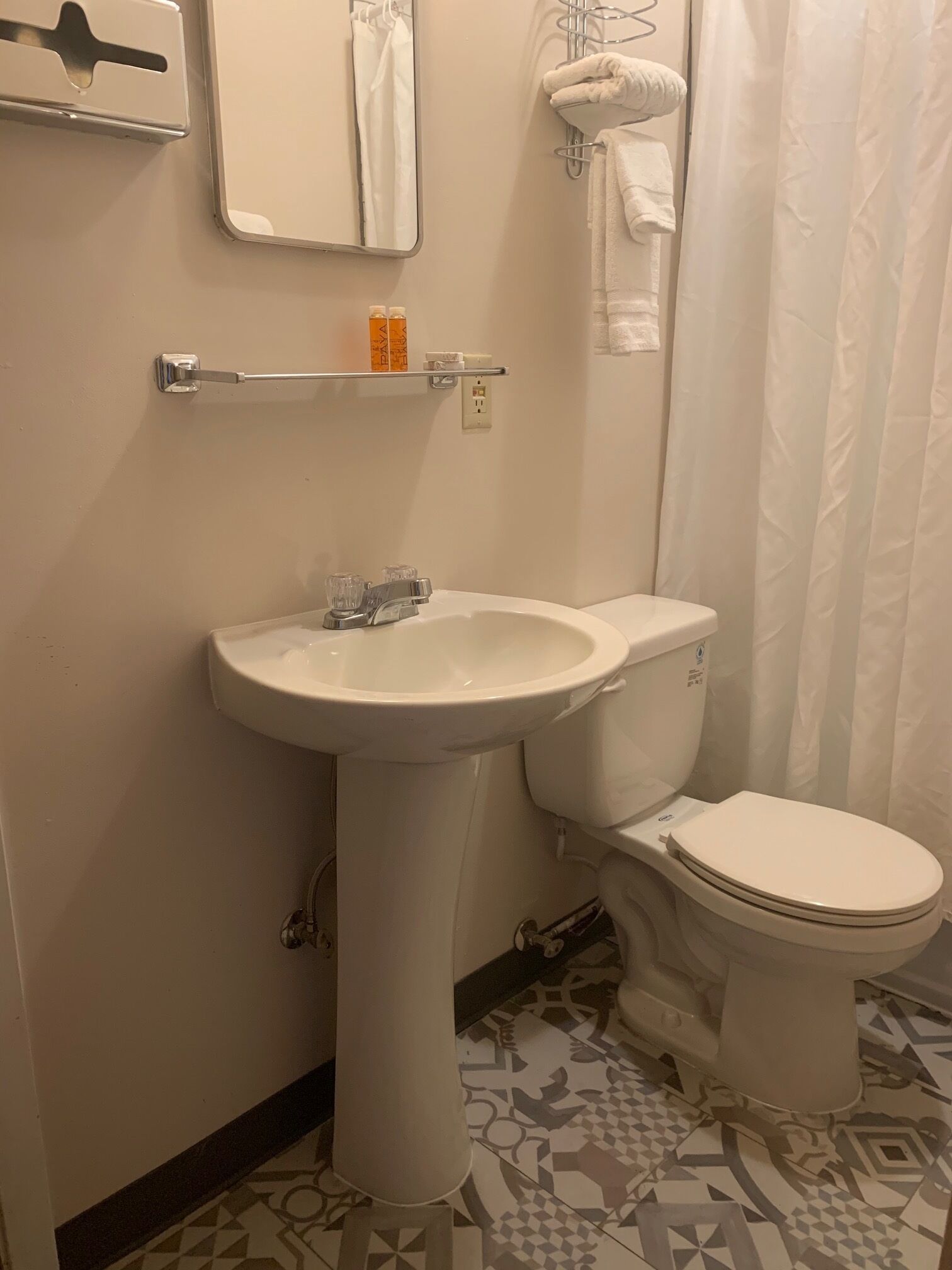 A bathroom with a pedestal sink, toilet, and a shower curtain.