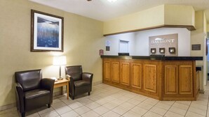A reception area with a wooden counter, two leather chairs, a framed picture on the wall, and a ceiling fan. - Baymont by Wyndham Billings (Billings)