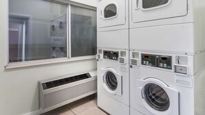 A laundry room with stacked washers and dryers, a window, and a vent. - Baymont by Wyndham Billings (Billings)