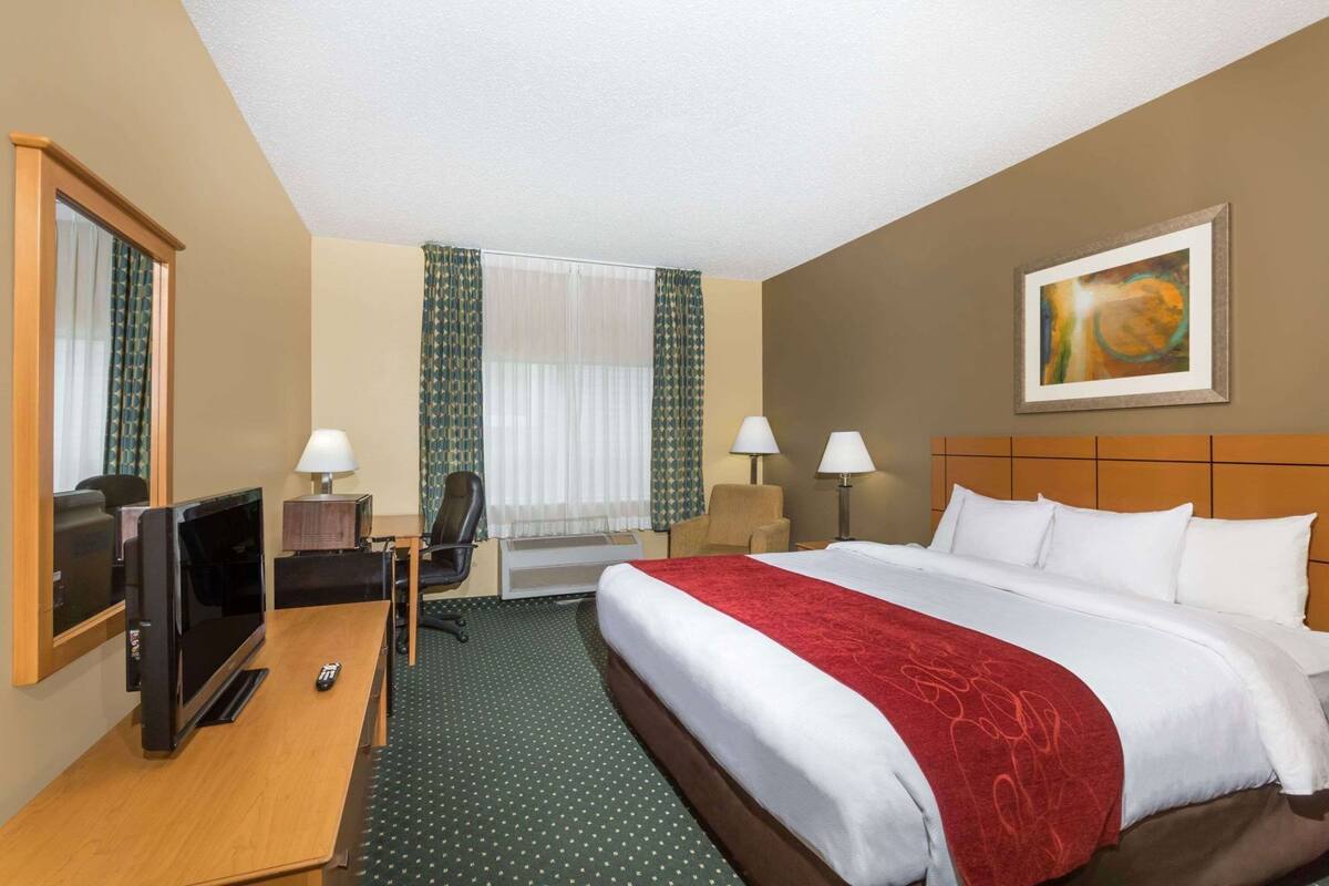 Ein Hotelzimmer mit Bett, Schreibtisch, Stuhl, Fernseher und Lampen.