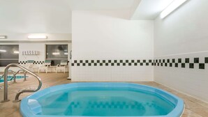 A rectangular indoor pool with a blue interior, surrounded by beige tiles. - Baymont by Wyndham Billings (Billings)