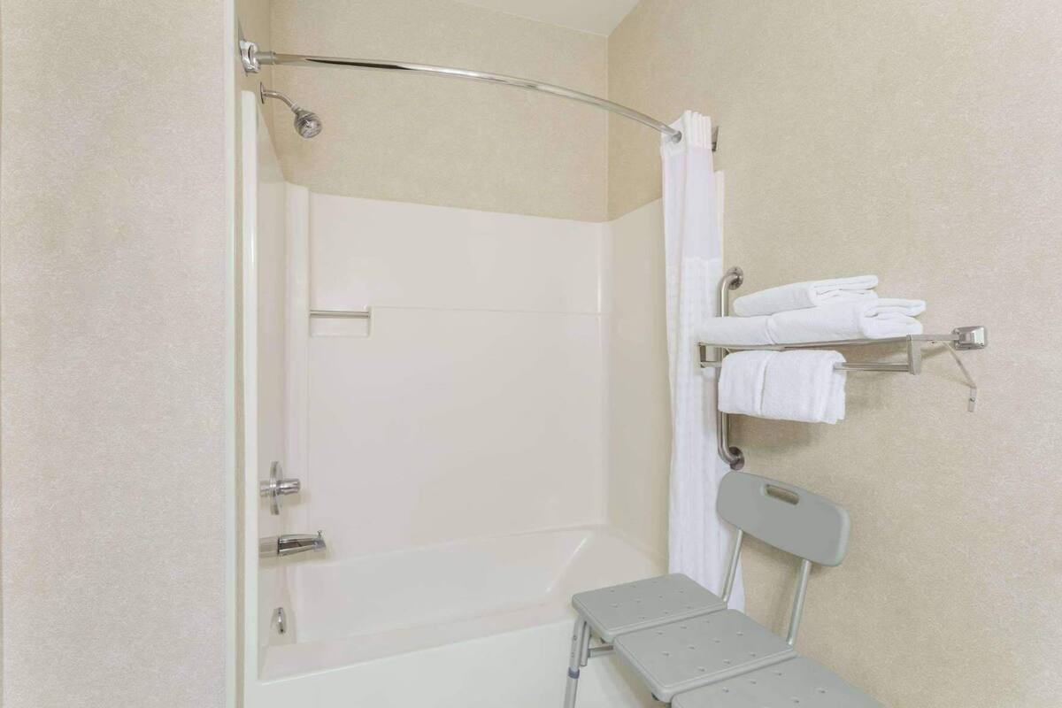Eine Dusche mit Glastür, einer Haltestange und einem Handtuchhalter mit gefalteten Handtüchern.