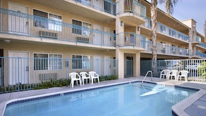 A multi-story building with balconies, a swimming pool, and outdoor seating. - Days Inn by Wyndham Riverside Tyler Mall (Riverside)