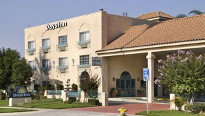 A Days Inn hotel with a beige facade, multiple balconies, and a covered entrance area. - Days Inn by Wyndham Riverside Tyler Mall (Riverside)