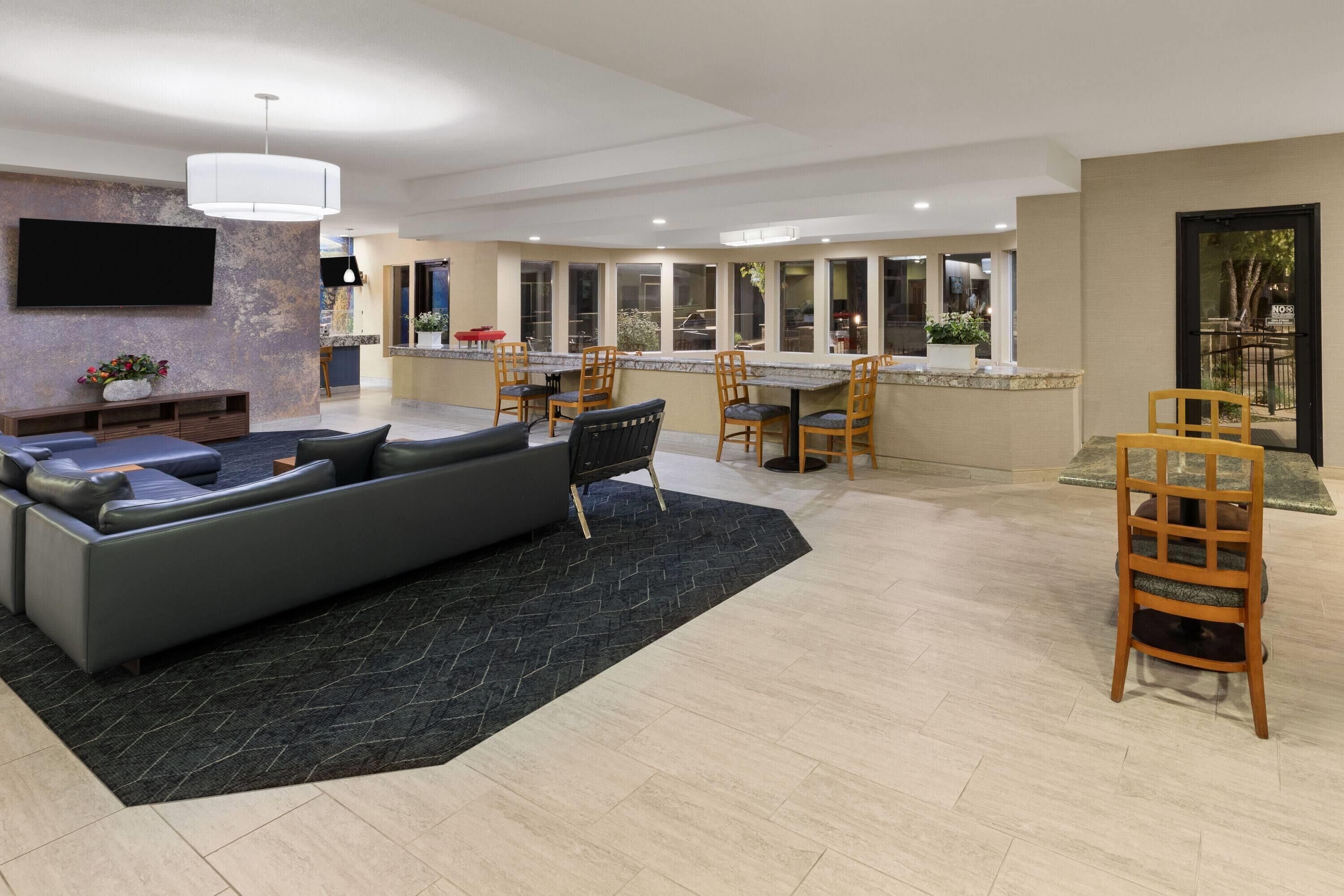 A spacious living area with a large sofa, a dining table with chairs, and a kitchen area with a bar counter.