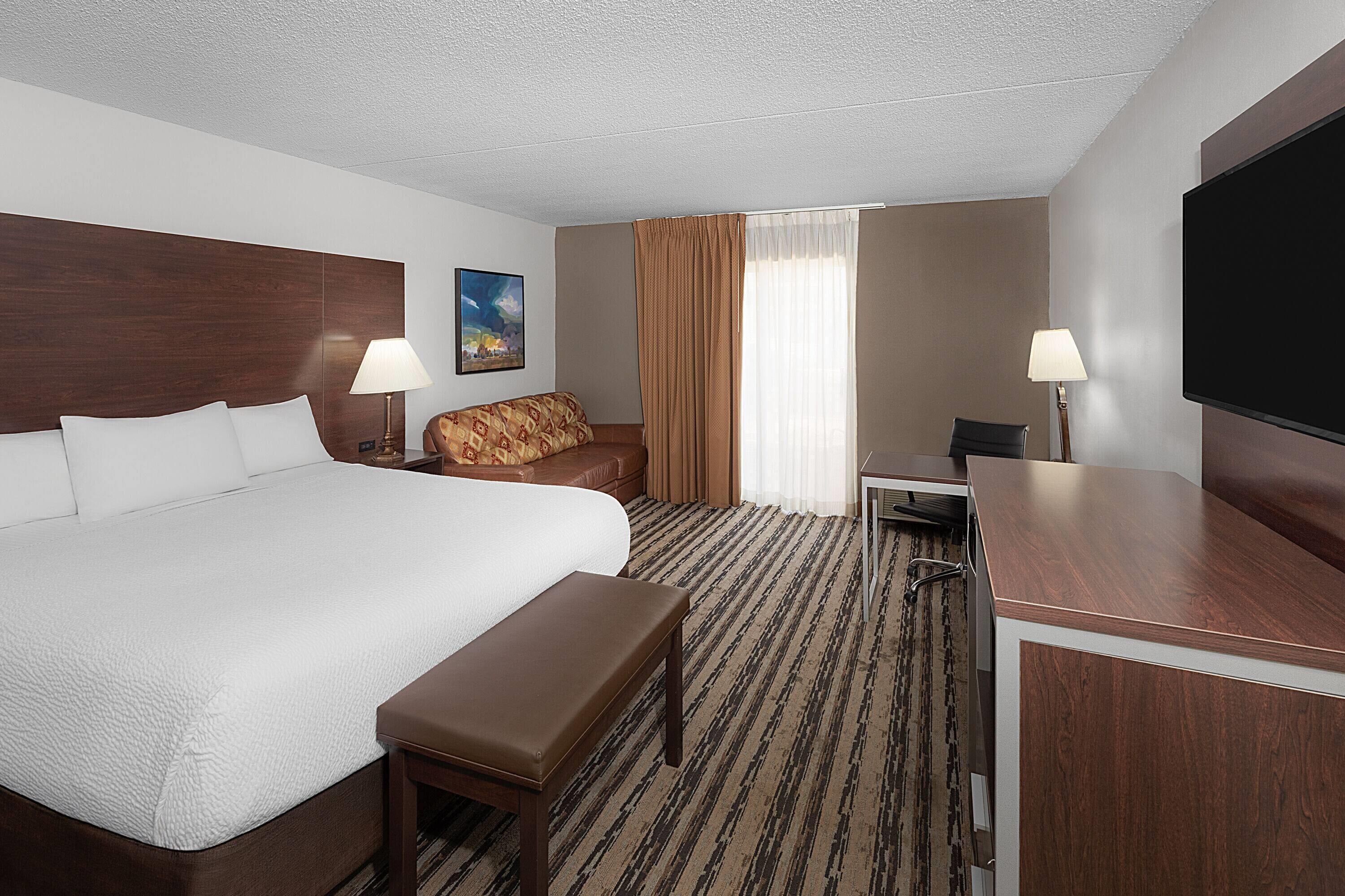 Una habitación de hotel con una cama grande, un sofá, un escritorio y una televisión.