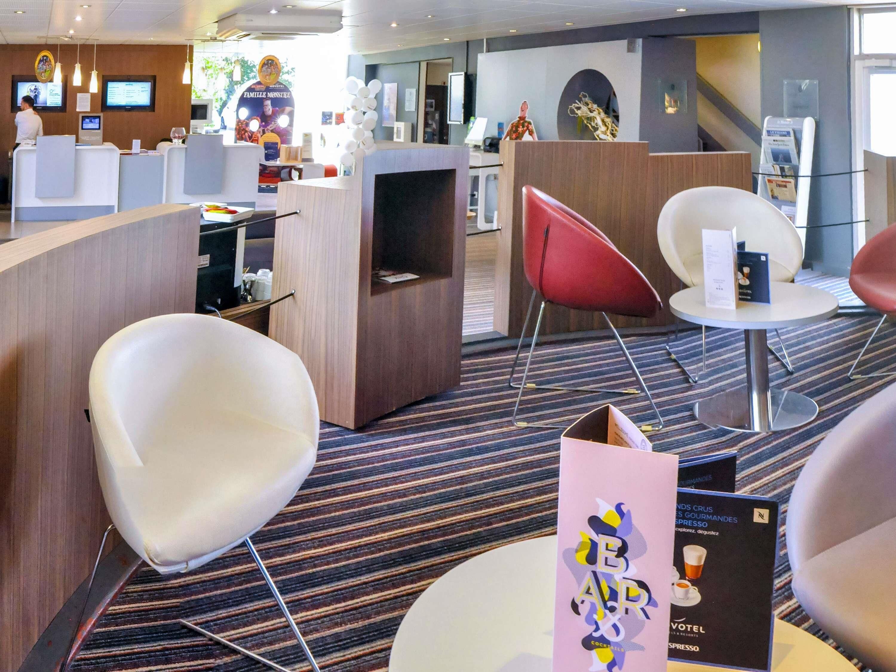 Un moderno vestíbulo de hotel con mostrador de recepción, zona de estar y un bar.