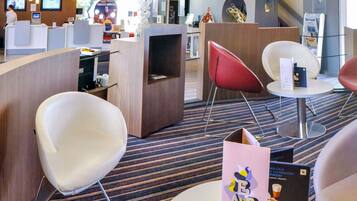 Un moderno vestíbulo de hotel con mostrador de recepción, zona de estar y un bar.