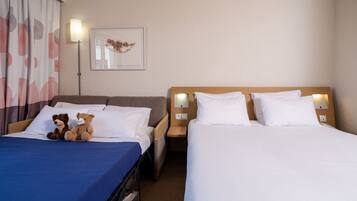A hotel room with two beds, a nightstand, a lamp, and a framed picture on the wall.