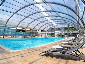 Ein überdachter Pool mit Liegestühlen und einer Glaskuppel.