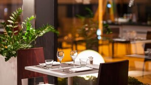 Un restaurante con una mesa preparada para dos personas, incluyendo copas de vino, vasos de agua y cubiertos.