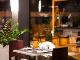 Un restaurante con una mesa preparada para dos personas, incluyendo copas de vino, vasos de agua y cubiertos.