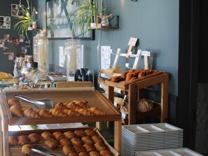 Eine Bäckertheke mit Gebäck, Brot, einer Kaffeemaschine und einer Speisekarte.