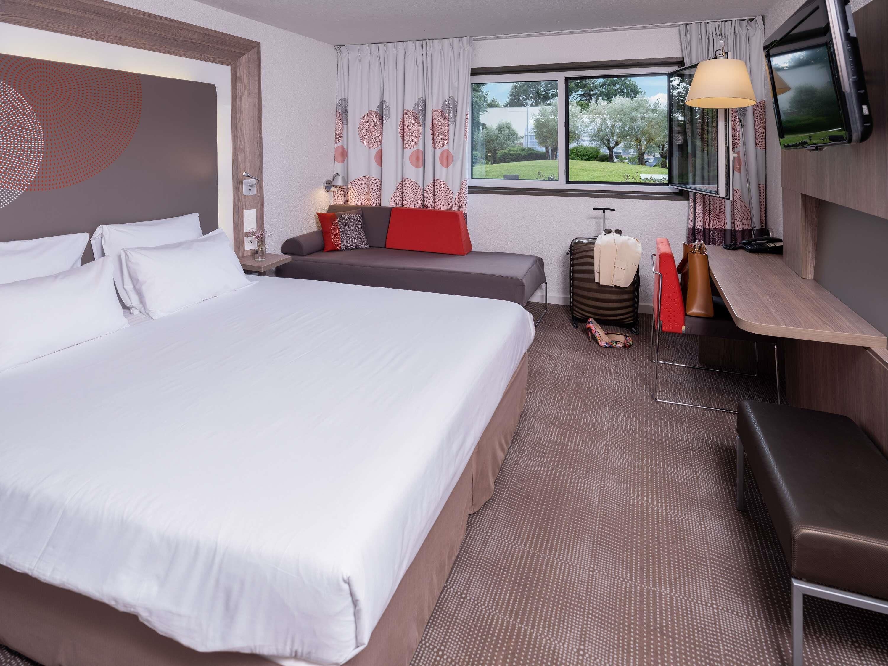 Una habitación de hotel con una cama grande, un sofá, un escritorio y una televisión.
