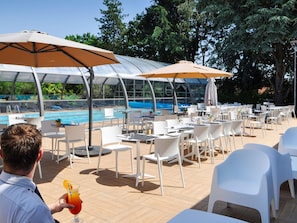 A poolside area with outdoor seating, umbrellas, and a pool view.