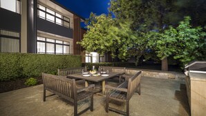 An outdoor patio with a wooden table and chairs, a barbecue grill, and a hedge. - The Sebel Bowral Heritage Park (Bowral)