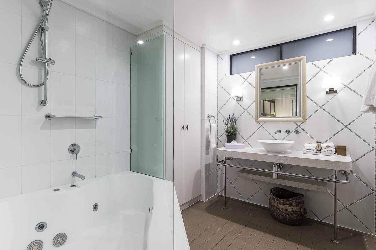 Un baño moderno con bañera, ducha, tocador y un espejo grande.