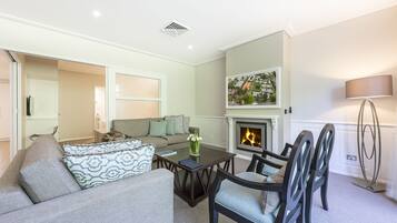 A living room with a sofa, chairs, a coffee table, a fireplace, and a painting on the wall.