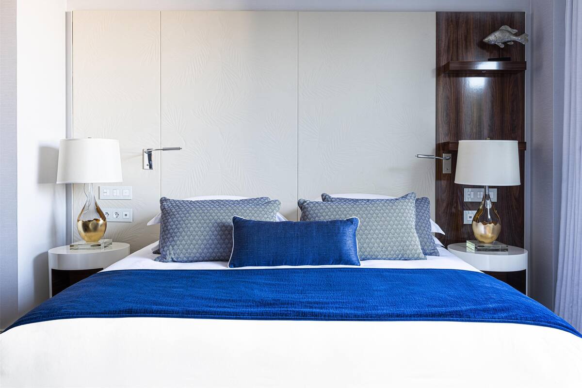 Une chambre d’hôtel moderne avec un grand lit, deux tables de chevet et une petite table d’appoint.