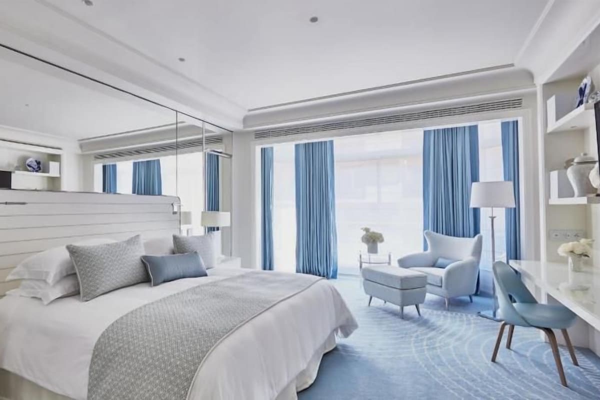 A modern hotel room with a large bed, bedside tables, a desk, and a chair.