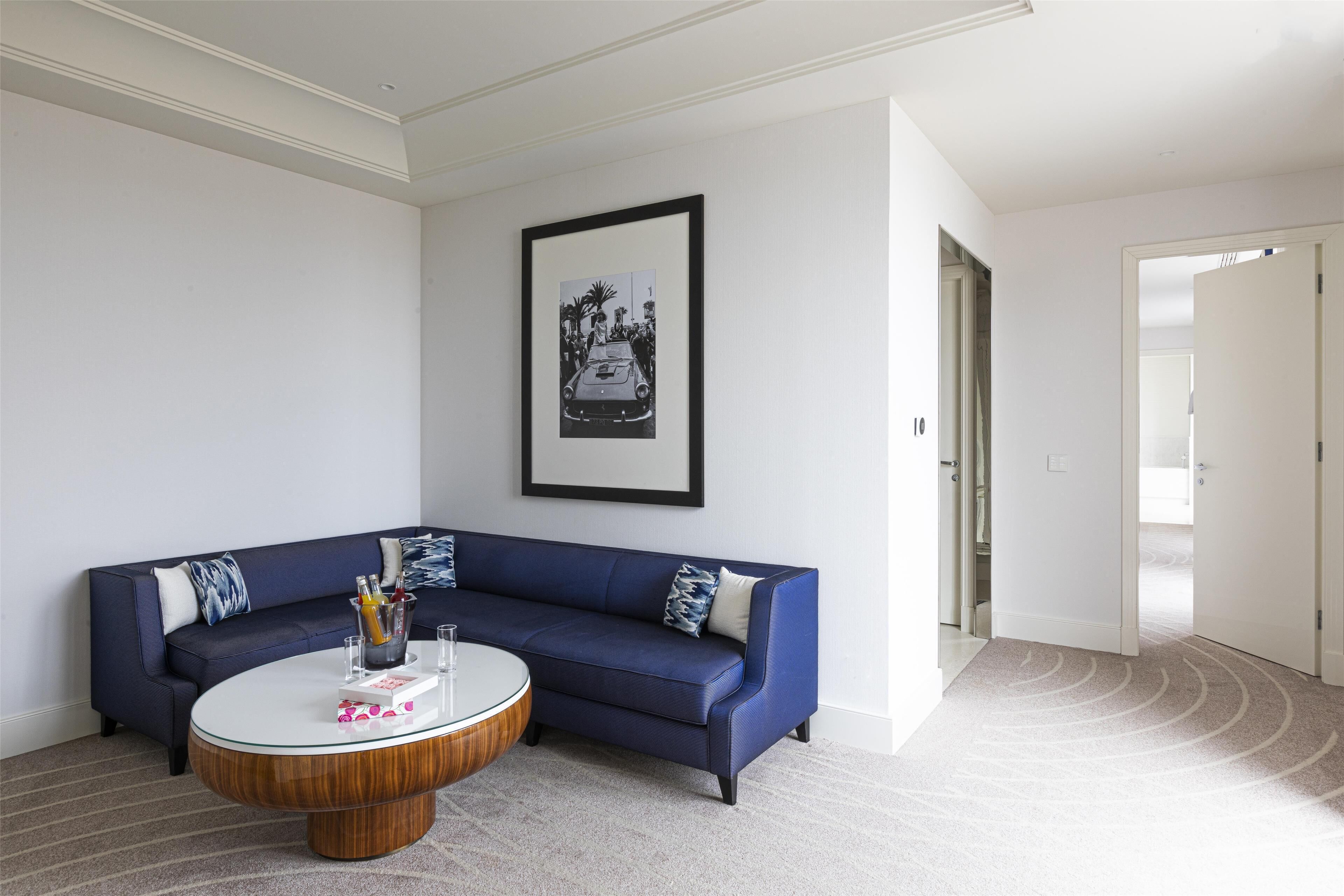 Un salon moderne avec un canapé bleu, une table basse ronde et un tableau encadré accroché au mur.