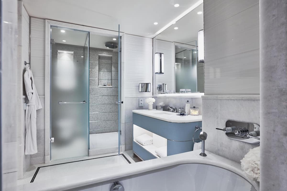 Une salle de bain moderne dotée d’une douche à parois de verre, d’une baignoire sur pieds et d’un meuble-lavabo avec un miroir.