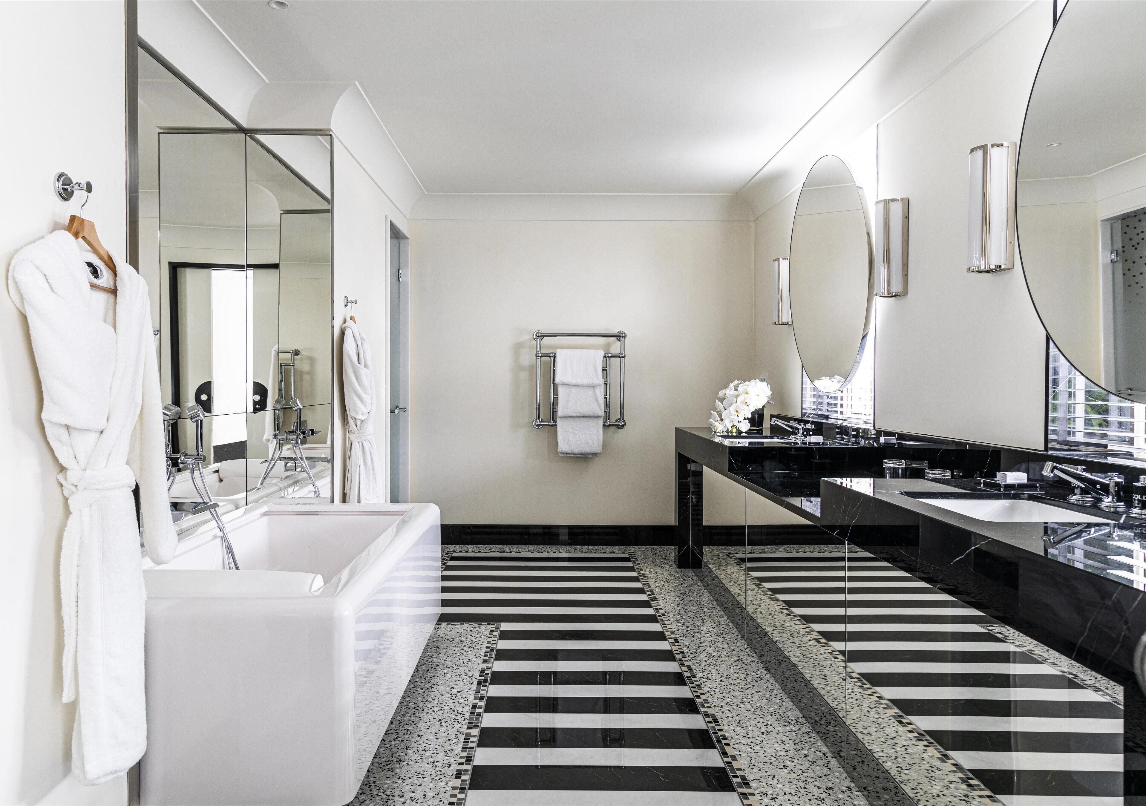 A modern bathroom with a large bathtub, two sinks, and a mirror.