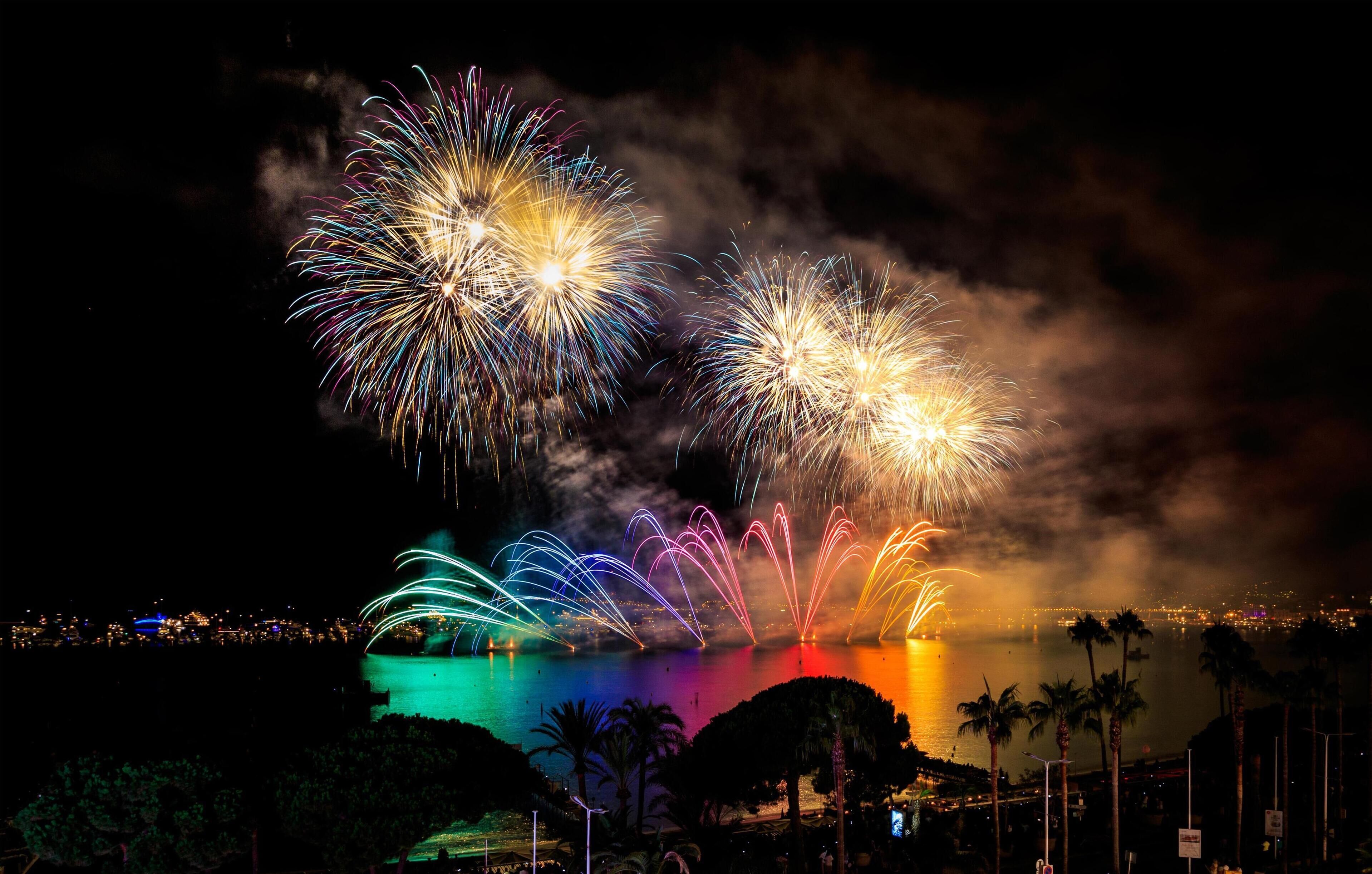 A nighttime view of a waterfront with fireworks display.