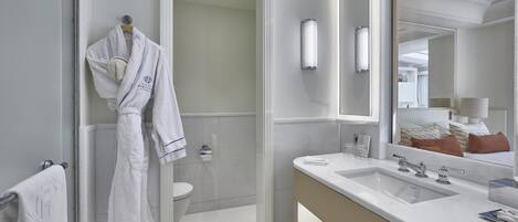 A modern bathroom with a glass shower enclosure, a white bathtub, a large mirror, and a vanity with a sink.