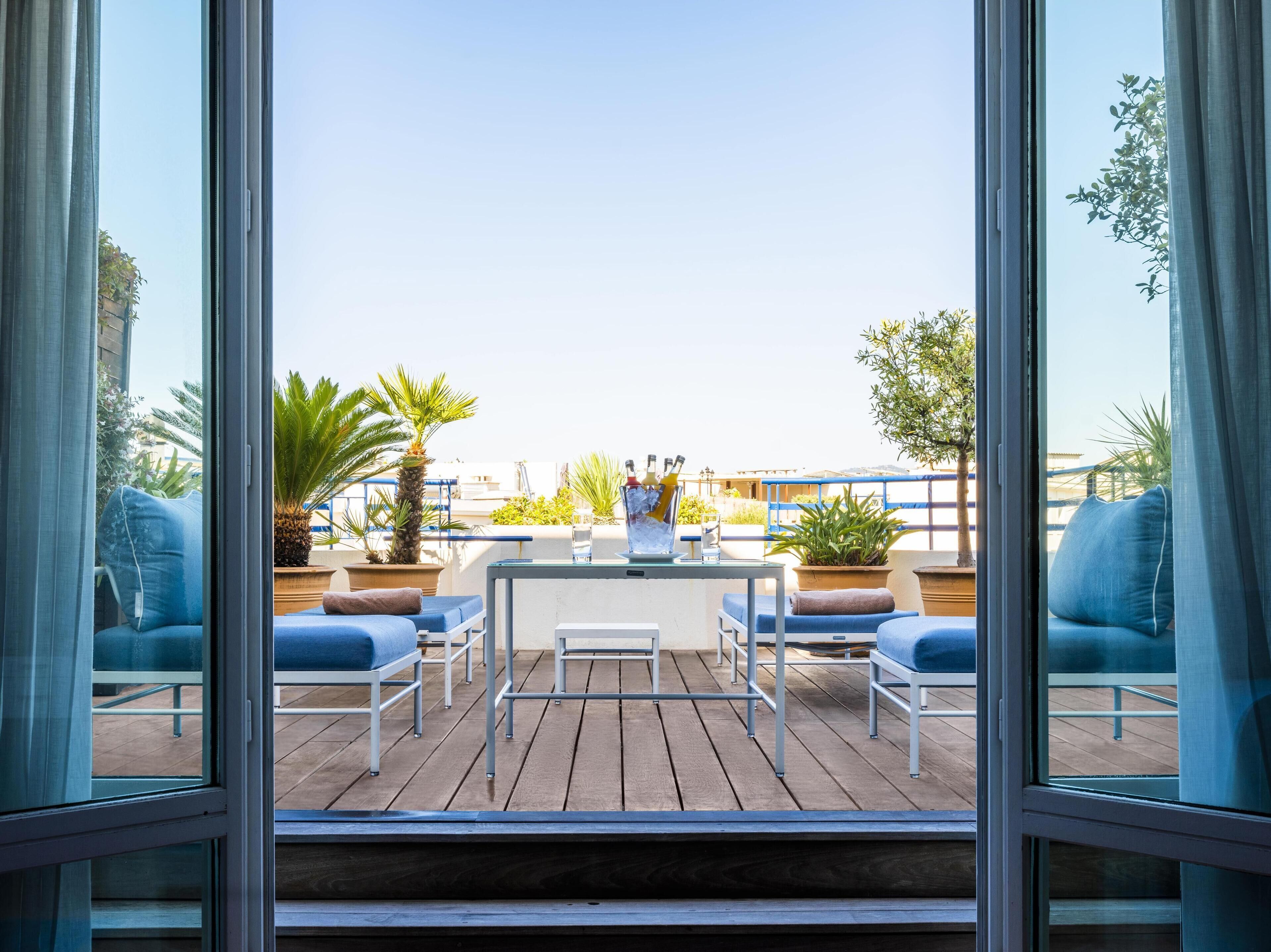 Une terrasse avec une table, des chaises et des plantes en pot.