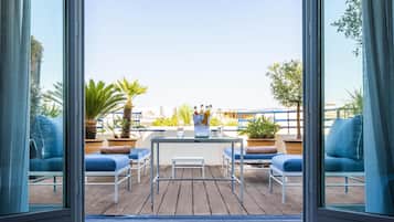 Una terraza con una mesa, sillas y plantas en macetas.
