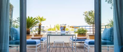 Um terraço com uma mesa, cadeiras e plantas em vasos.