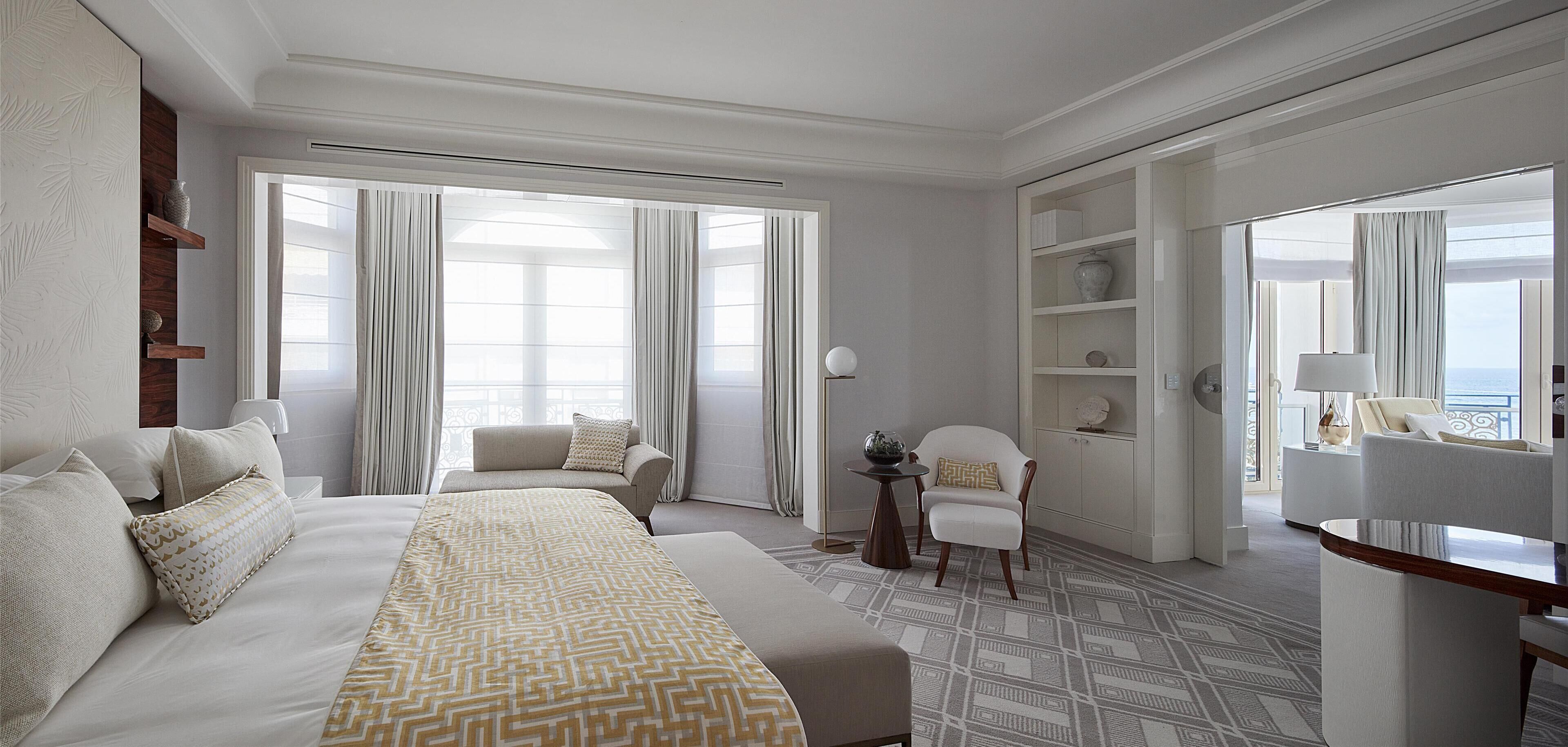 Ein Hotelzimmer mit einem großen Bett, einer Couch, einem Sessel, einem kleinen Tisch und einem Bücherregal.
