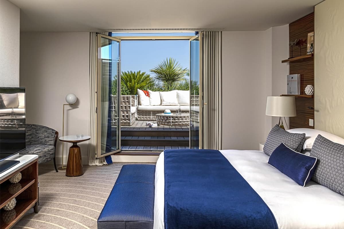 Une chambre d’hôtel avec un grand lit, une télévision, une petite table et un balcon avec un canapé.