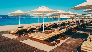A beachside lounge area with sunbeds and umbrellas, overlooking the sea.