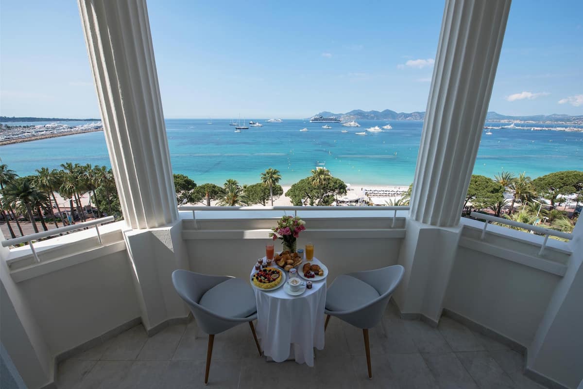 Un balcon avec une table préparée pour le petit-déjeuner, donnant sur une plage et la mer.