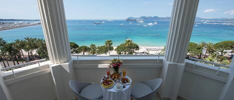 Varanda com mesa posta para o café da manhã, com vista para a praia e o mar.