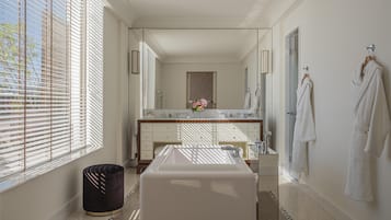 A modern bathroom with a large mirror, a bathtub, and a vanity.