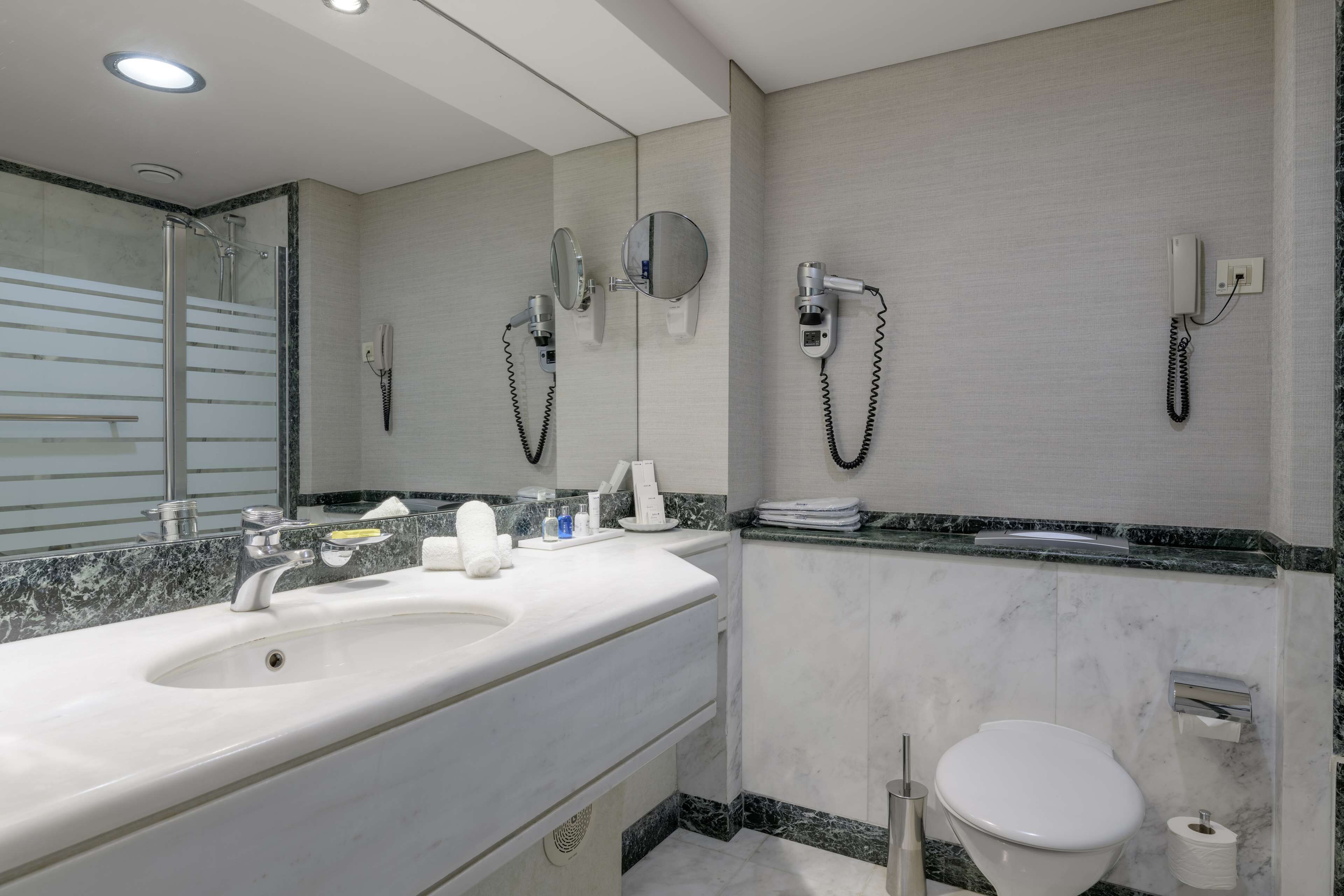 Een moderne badkamer met een groot wastafel, twee spiegels, een toilet en een douche.