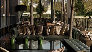 A modern interior with a sofa set, decorative trees, and a ceiling with leaf patterns. - Radisson Blu Park Hotel, Athens (Athens)