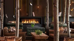 A cozy lounge area with leather sofas, a fireplace, and decorative trees. - Radisson Blu Park Hotel, Athens (Athens)
