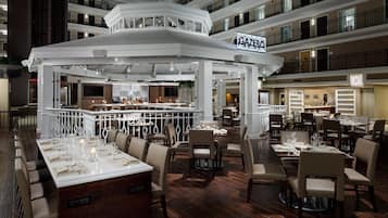 Un restaurant à plusieurs niveaux, doté d’un bar central, de nombreuses tables et offrant une vue sur les étages supérieurs.