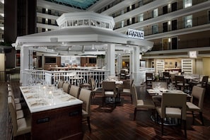 Un restaurant à plusieurs niveaux, doté d’un bar central, de nombreuses tables et offrant une vue sur les étages supérieurs.