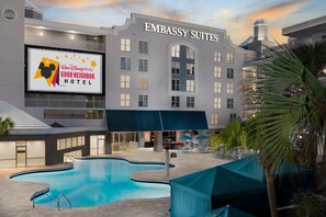 Un hotel con piscina, zona de estar exterior y un cartel que indica Hotel Vecino de Buena Vecindad de Walt Disney World.