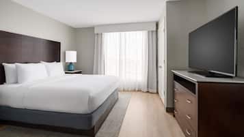 A hotel room with a large bed, a flat-screen TV, a nightstand, and a dresser.