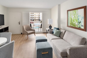 Un salon moderne avec un téléviseur à écran plat, un canapé, un fauteuil, une table et un tableau.