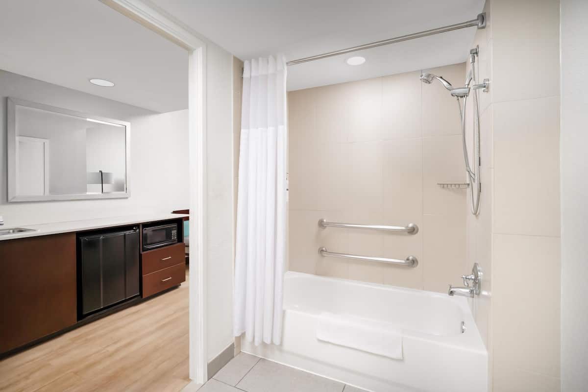 Un baño moderno con bañera, ducha y un espejo grande.