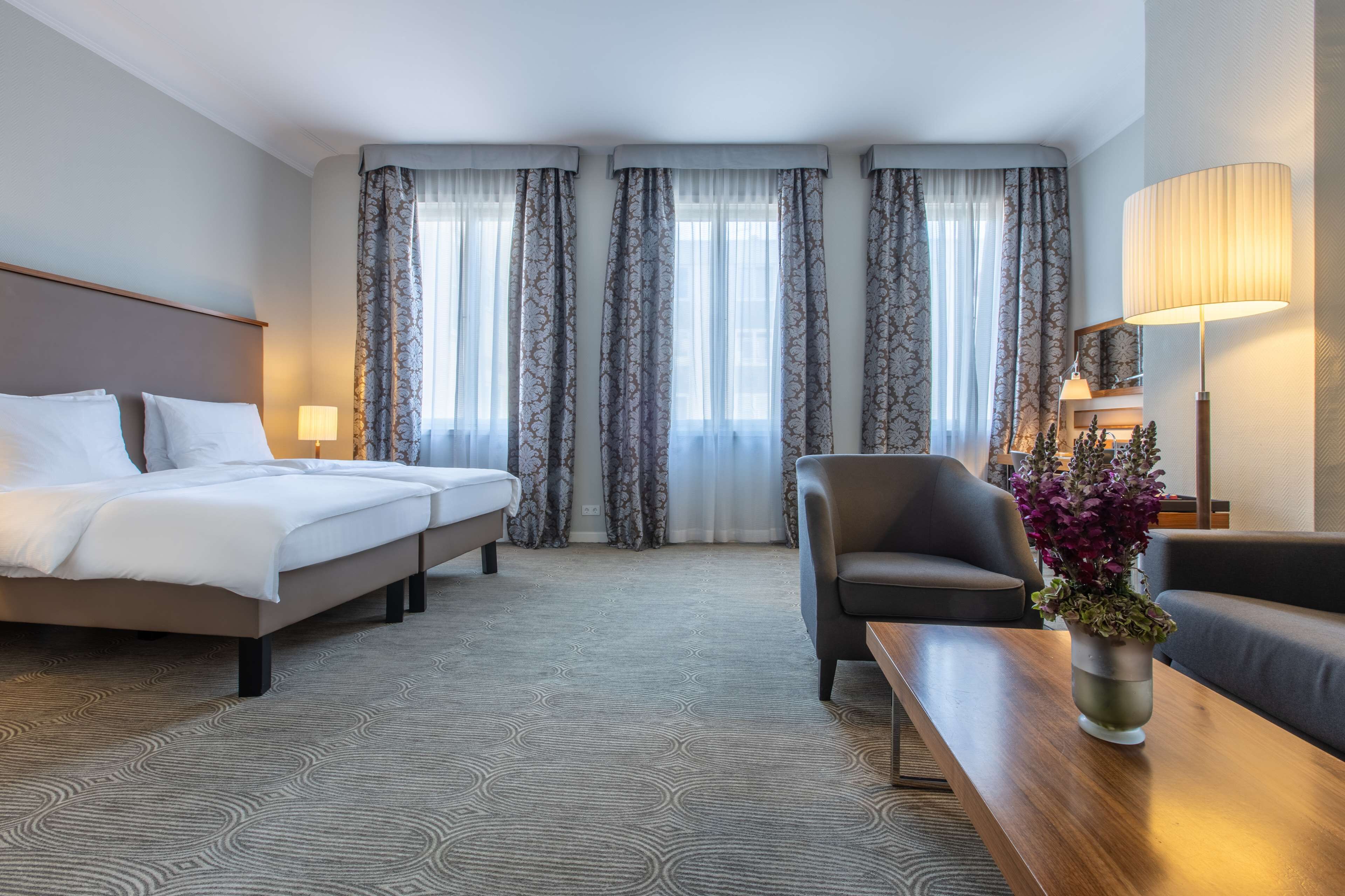 Ein Hotelzimmer mit einem Bett, einem Sessel, einem Sofa, einem Tisch und einer Lampe.